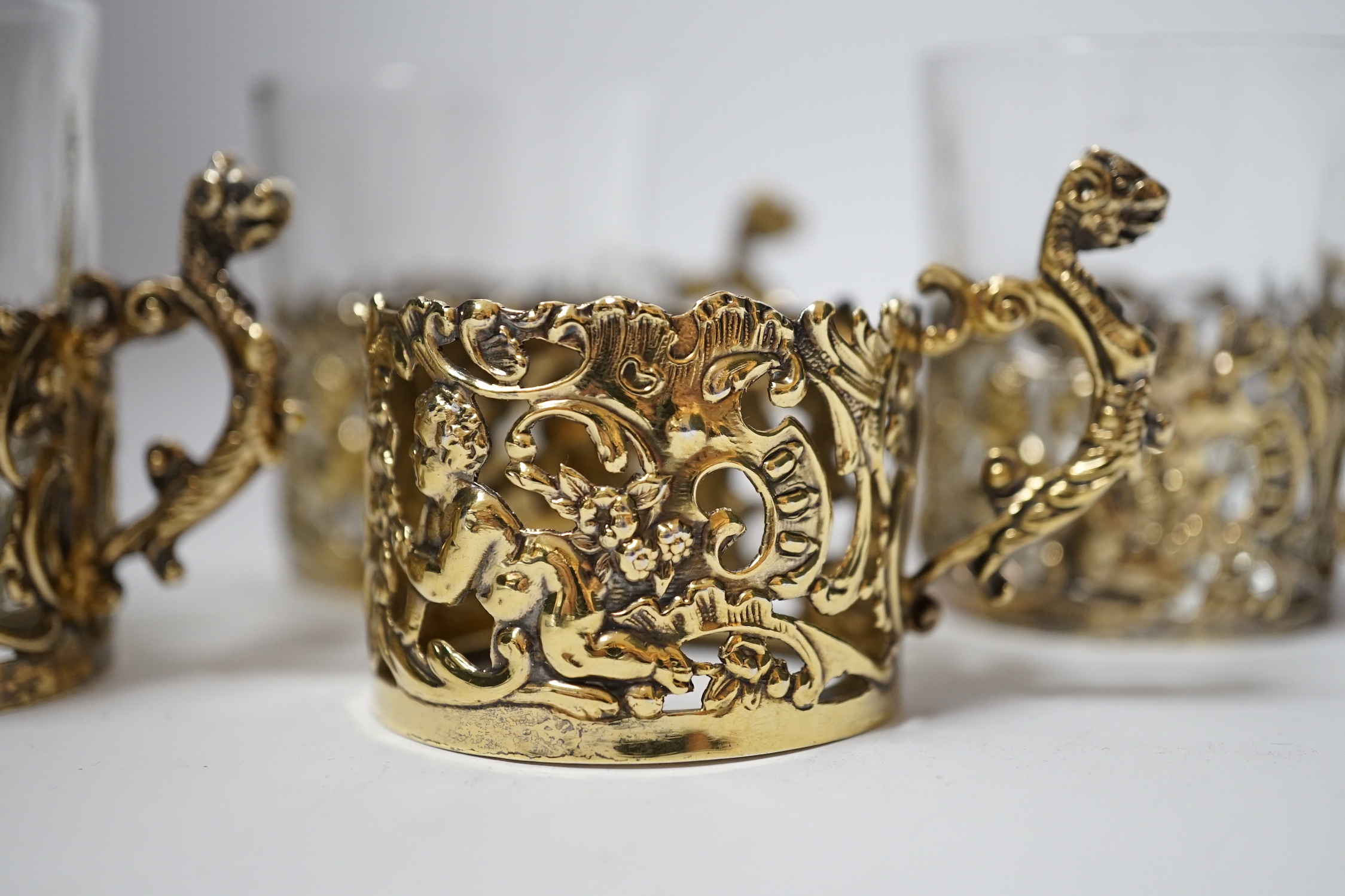 A set of four late Victorian pierced silver gilt coffee can holders, by William Comyns, Birmingham, 1897, with three glass inserts only